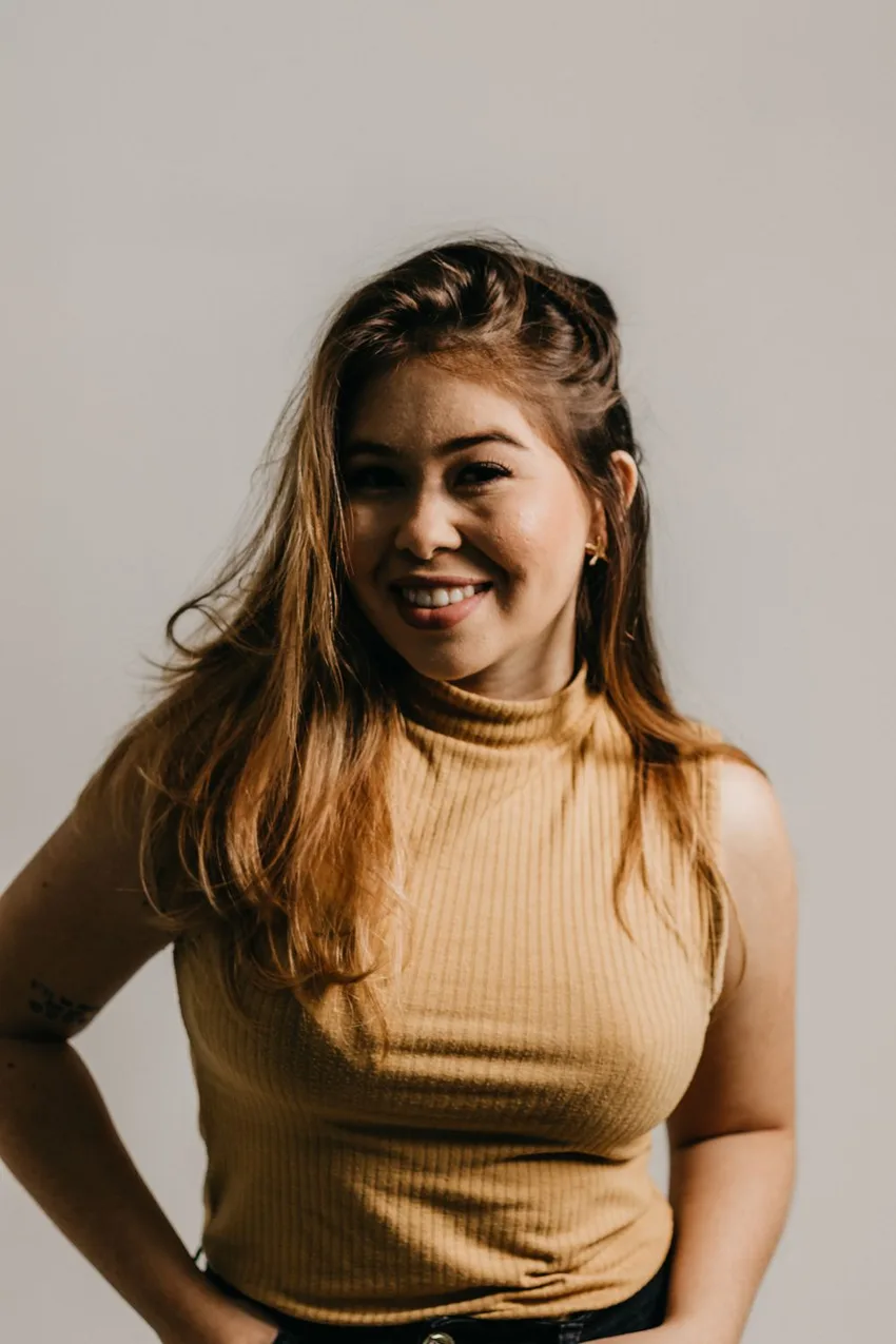 A woman in relaxed clothing smiling in soft light